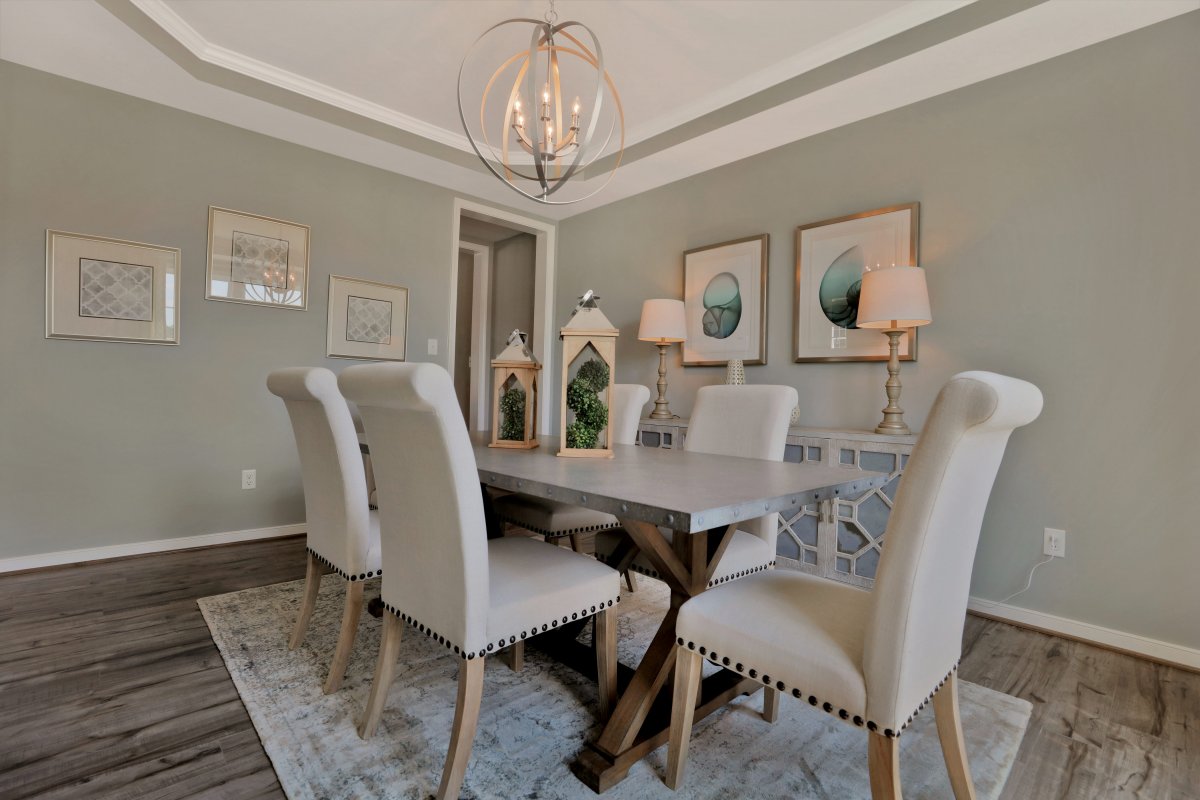 Savannah plan dining room in gray with a tray ceiling, wood floors and modern chandelier in Greenwich Walk in Mosely, VA