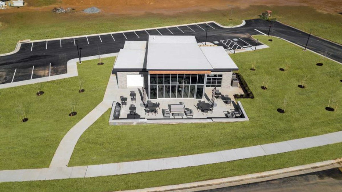 An aerial view  of the Connexion Clubhouse with connected sidewalk and parking lot, and a green lawn.
