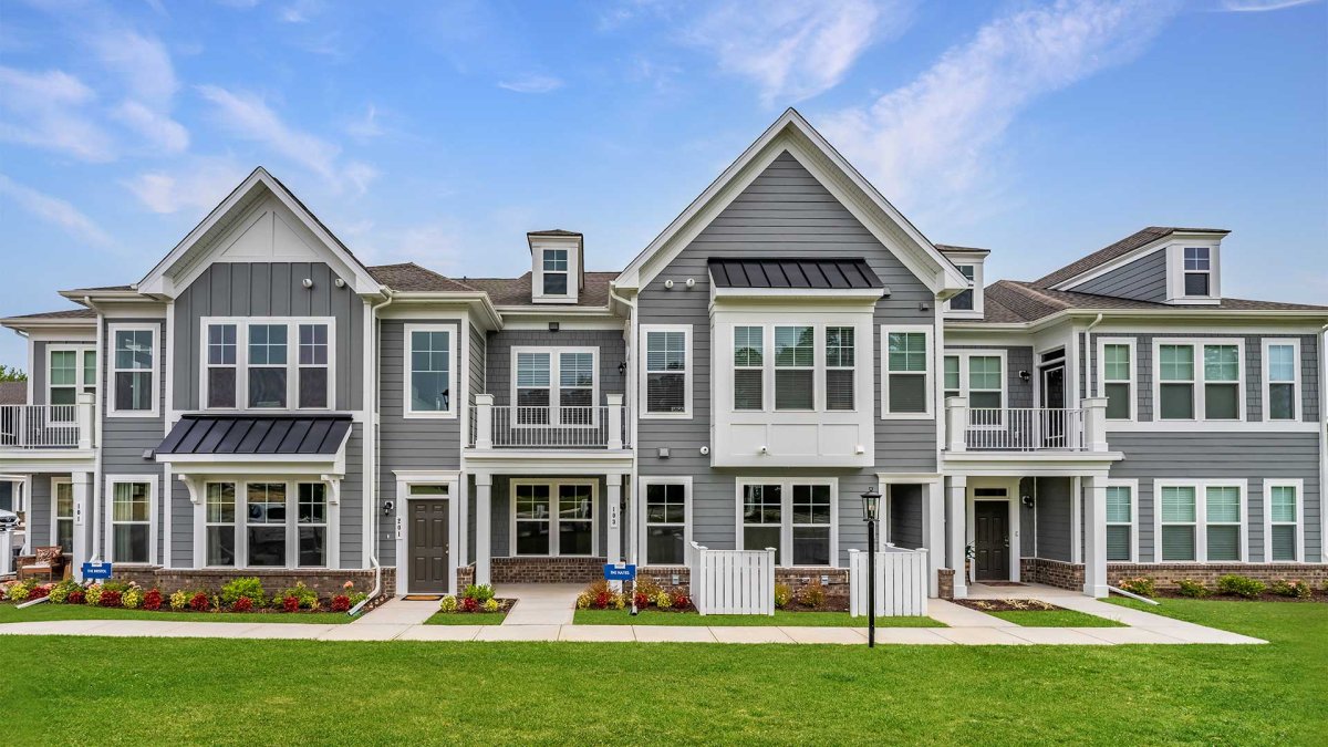 Exterior of private entry condos at The Pointe at Twin Hickory by HHHunt Homes, featuring gray siding, white trim, balconies, and landscaped walkways.