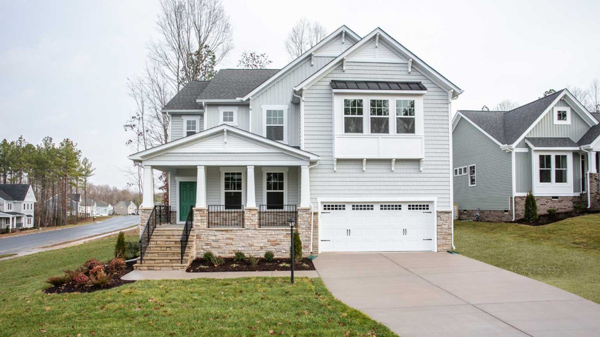 Exterior of the Fleetwood floor plan, Bungalow A elevation, by HHHunt Homes at The Summit At Morgan Ridge, featuring craftsman-style columns, stacked stone accents, light gray siding, a covered front porch, and a two-car garage with carriage-style doors.