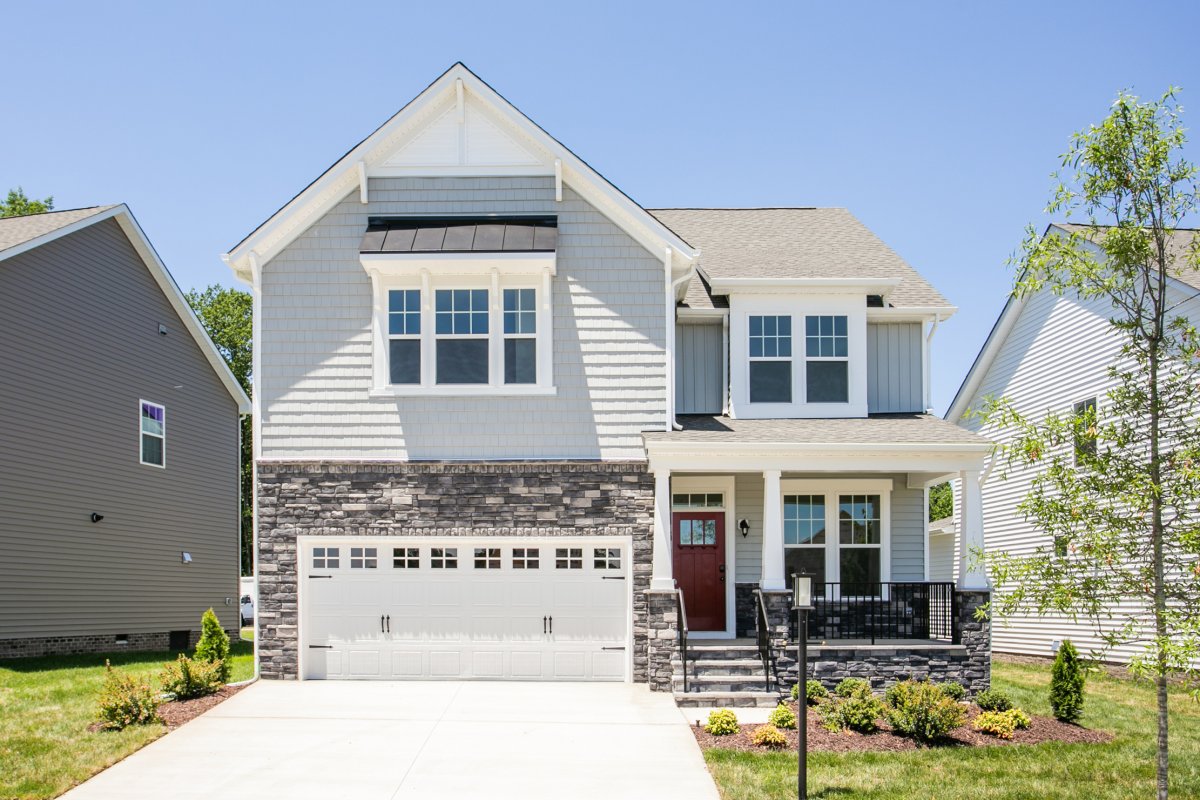 Front exterior of the Jarvis floor plan (Bungalow C elevation) at Tyson's Trail Estates by HHHunt Homes, featuring stone accents, a red front door, and a covered porch with white columns.
