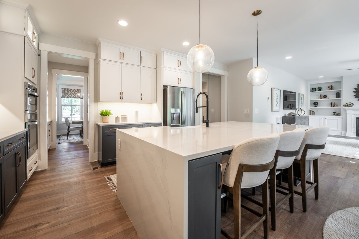Kitchen in the Grayson floor plan at Tyson’s Trail Estates by HHHunt Homes, featuring a large waterfall island with bar seating, pendant lighting, two-tone cabinetry, and stainless steel appliances.