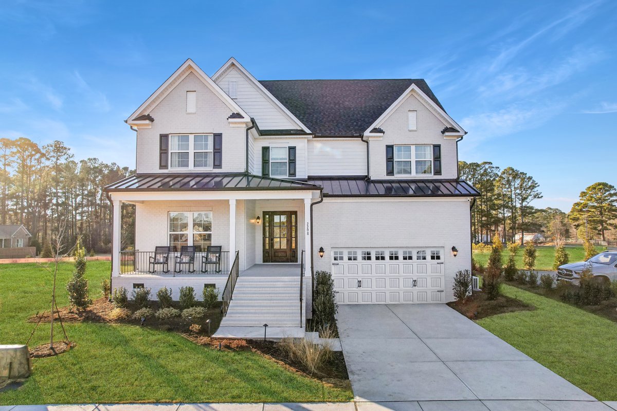 Exterior of Heritage A elevation for Latham floor plan by HHHunt Homes at Bridlewood, featuring covered porch, two-car garage, white brick siding, and black accents.