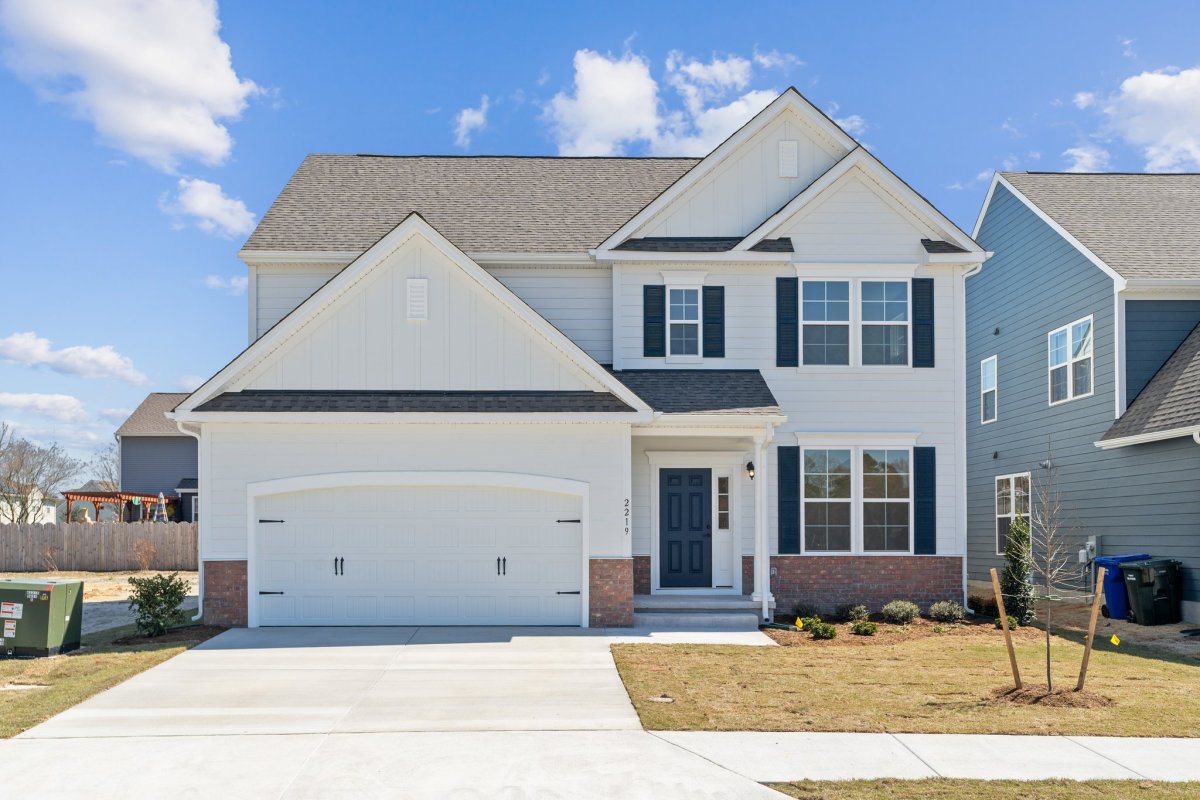 Exterior of the Franklin floor pan (Heritage A elevation) at Fawn Valley by HHHunt Homes, featuring two-car garage, brick accents, and off-white batten and board siding with dark blue shutters.
