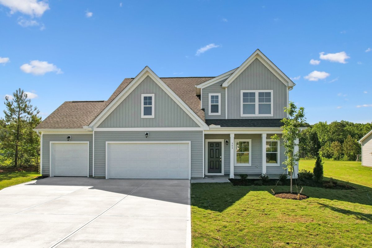 Exterior of the Maxwell floor plan (Farmhouse elevation) by HHHunt Homes at Oak Meadow, featuring a large driveway, three-car garage, and covered front porch.