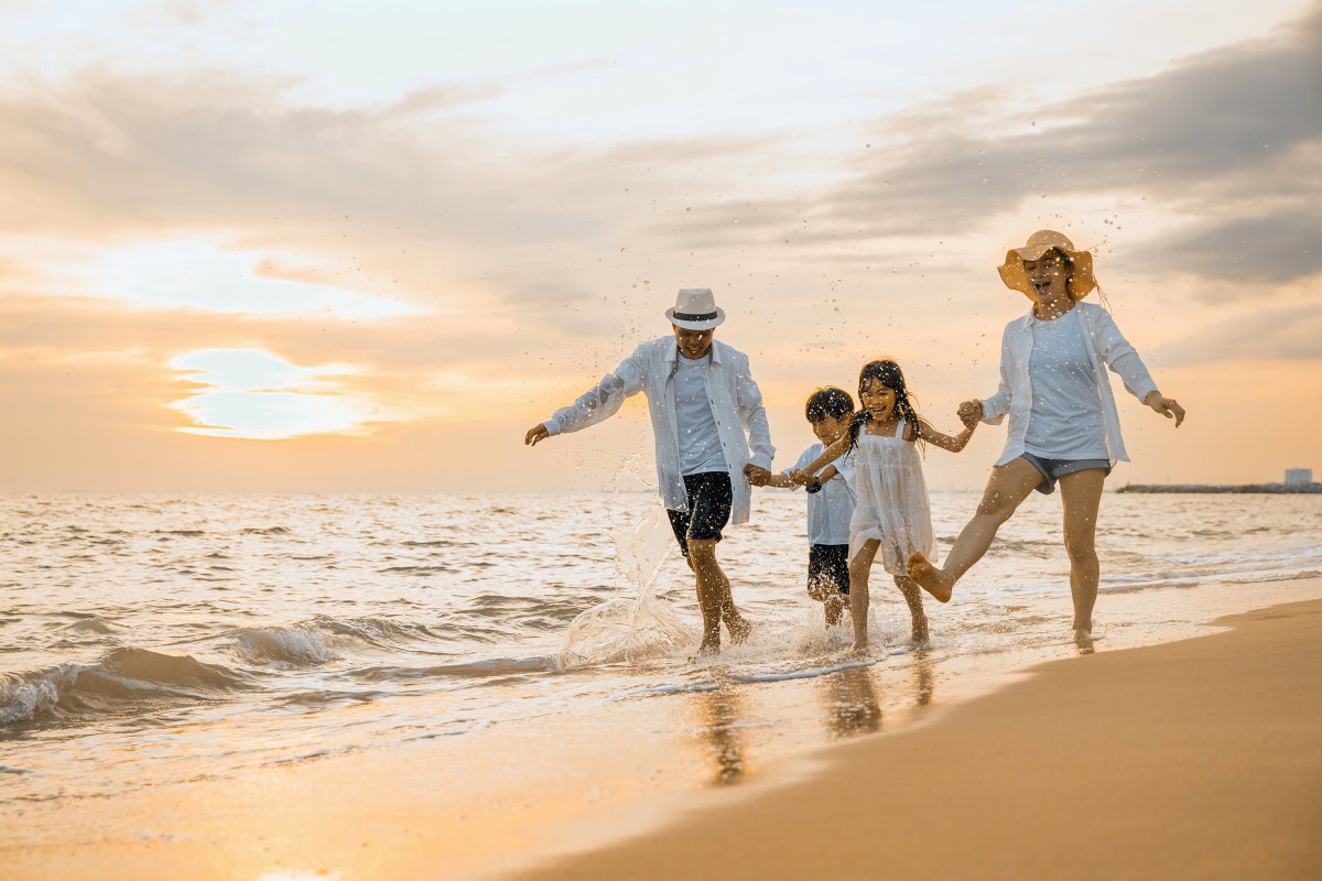 A mother and father running down the beach with their two kids.