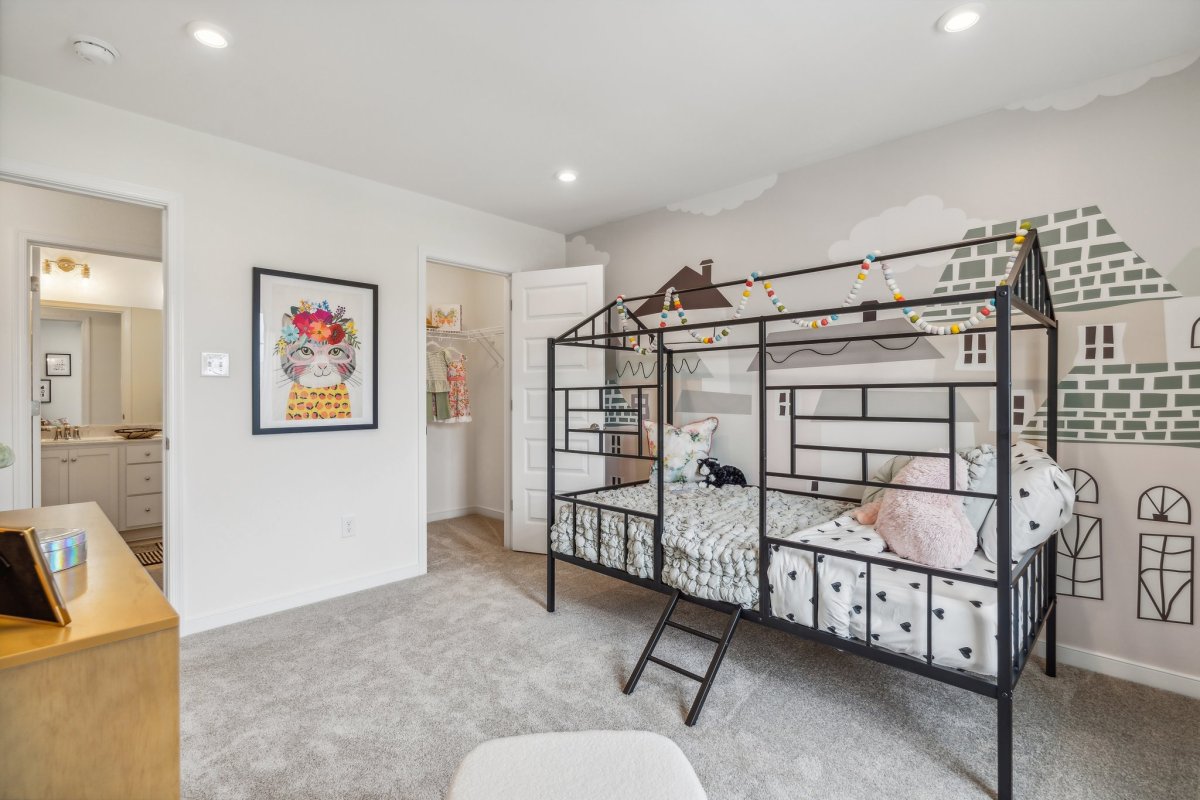 Kids bedroom in a Granite Ridge townhome by HHHunt Homes with house-frame bunk bed, playful mural, and carpet.