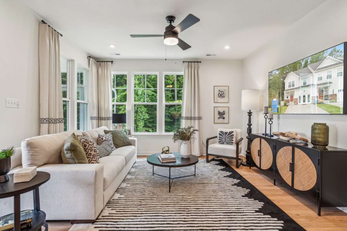 Family room in a Granite Ridge townhome by HHHunt Homes with large windows, neutral sofa, and modern décor.