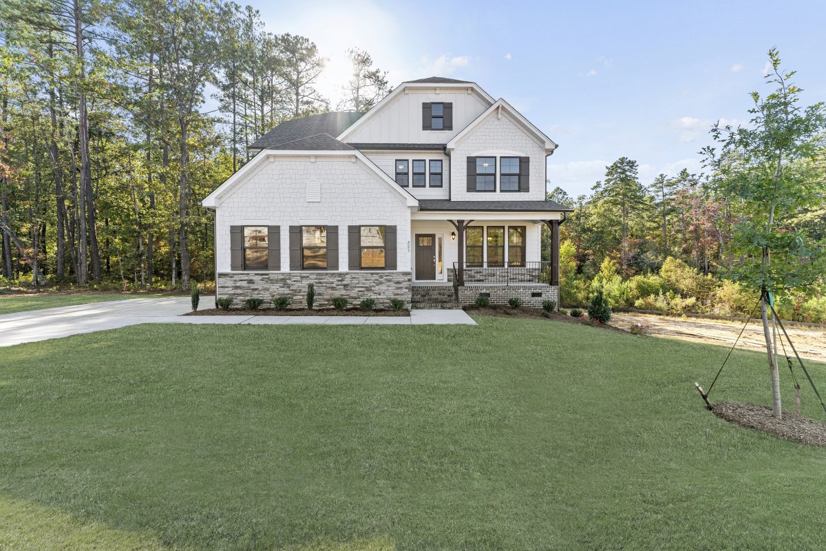 Front exterior rendering of the Grayson floor plan (European C elevation) at Bethesda Forest by HHHunt Homes, showcasing a two-story home with mixed siding, stone accents, gabled rooflines, covered front porch, and landscaped yard surrounded by trees.