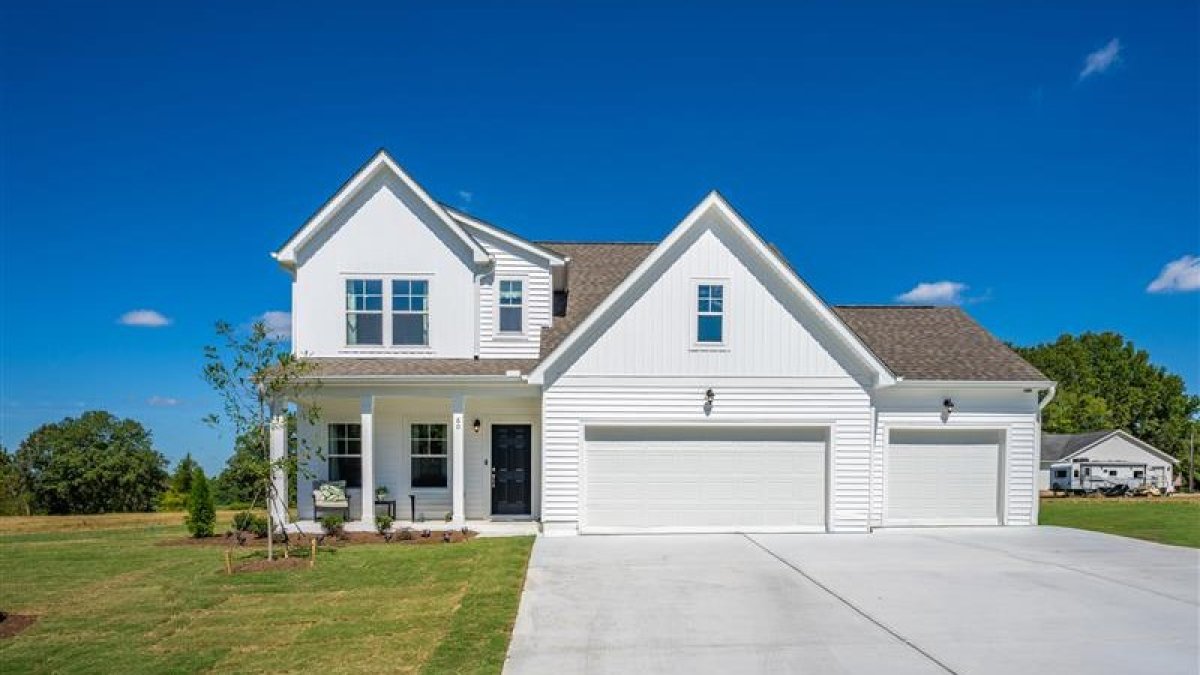 Exterior of the Maxwell floor plan (Farmhouse elevation) by HHHunt Homes at Oak Meadow, featuring a large driveway, three-car garage, and covered front porch.