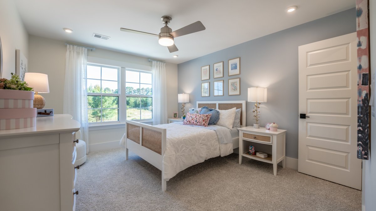 Bedroom in the Chatham floor plan at Tyson's Trail Estates by HHHunt Homes, featuring a full bed, nightstand and tons of natural light.