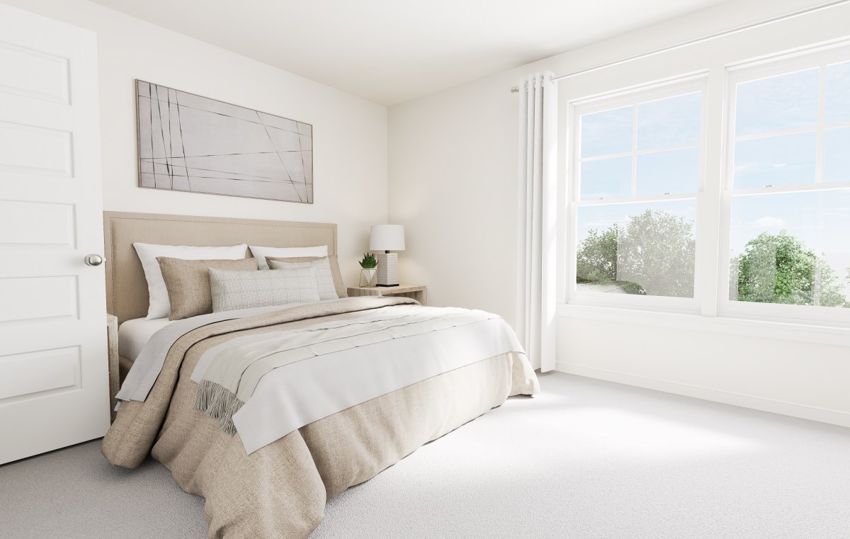 Primary suite in the Amherst floor plan by HHHunt Homes at Edgebrook, featuring a neutral-toned bedroom with upholstered bed, nightstand, and large windows providing natural light.